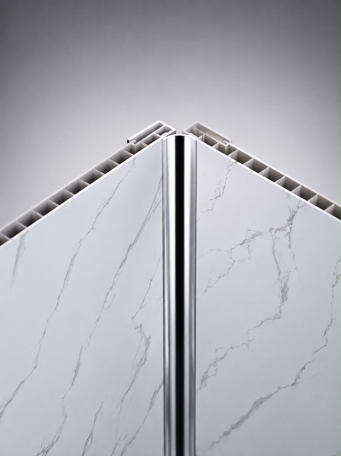 A close-up studio shot of a polished metallic silver corner trim piece positioned vertically between two white marble-patterned panels with gray veining, set against a gradient gray background.
