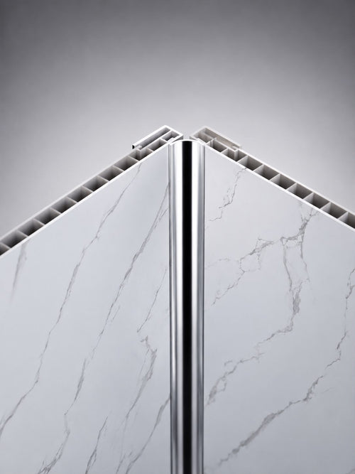 A close-up studio shot of a polished metallic silver corner trim piece positioned vertically between two white marble-patterned panels with gray veining, set against a gradient gray background.